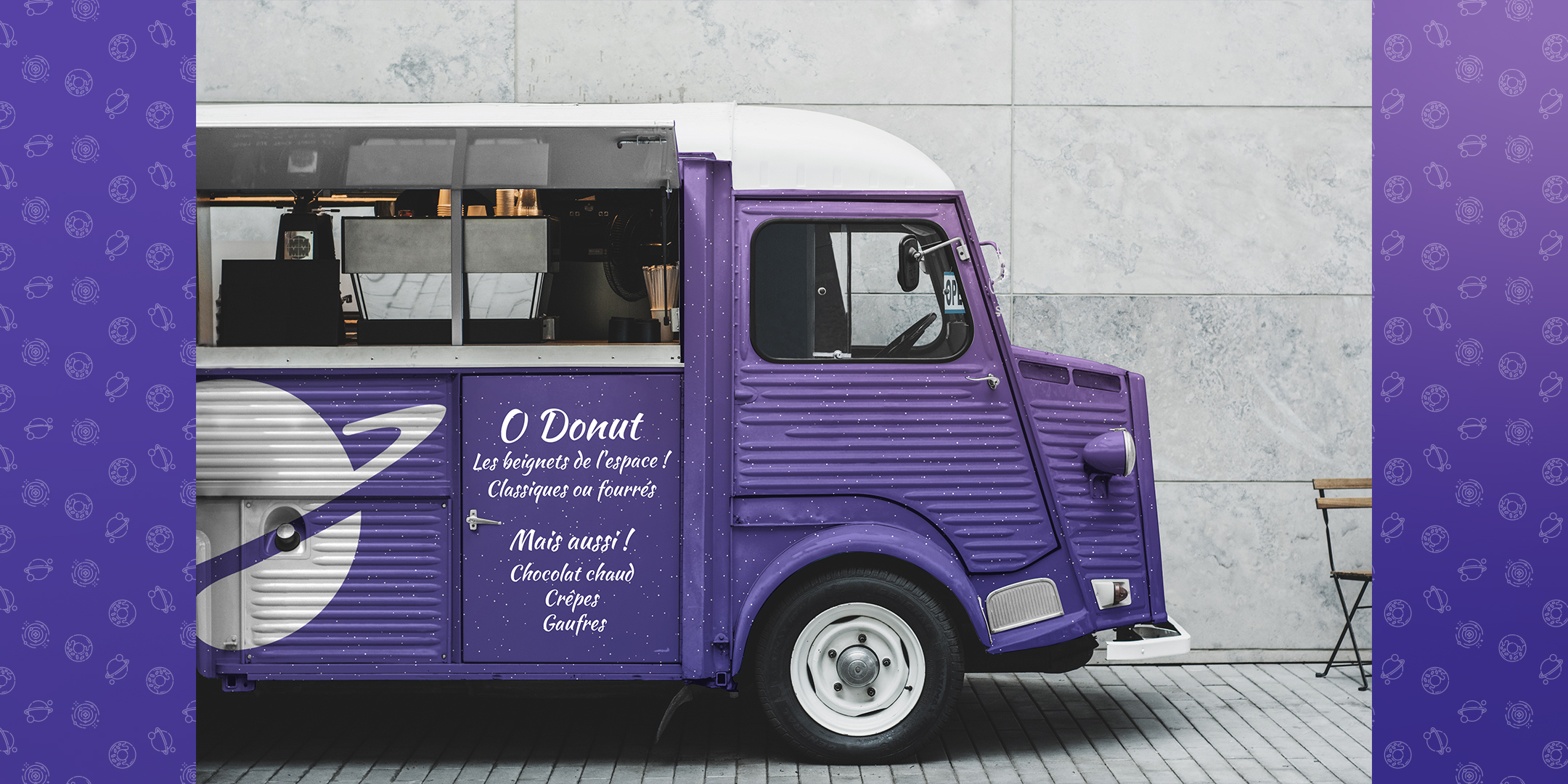 Photographie du camion O Donut vu de profil. Il est fait a partir d'un vieux van avec le toit blanc arrondi et de gros phares ronds à l'avant. Le camion est peint dans les tons violets et parsemé de petits points blancs évoquant les étoiles. Le logo de O Donut est peint en blanc en gros sur le flan arrière du véhicule, et le menu est inscrit en blanc sur la porte arrière. La partie supérieure est ouverte, permettant de vendre depuis le camion.